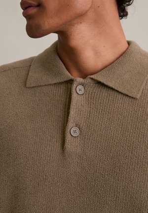Polo shirt marrone con texture, caratterizzato da un tessuto a coste, un colletto classico e due bottoni rotondi, che mette in mostra un materiale morbido e confortevole.
