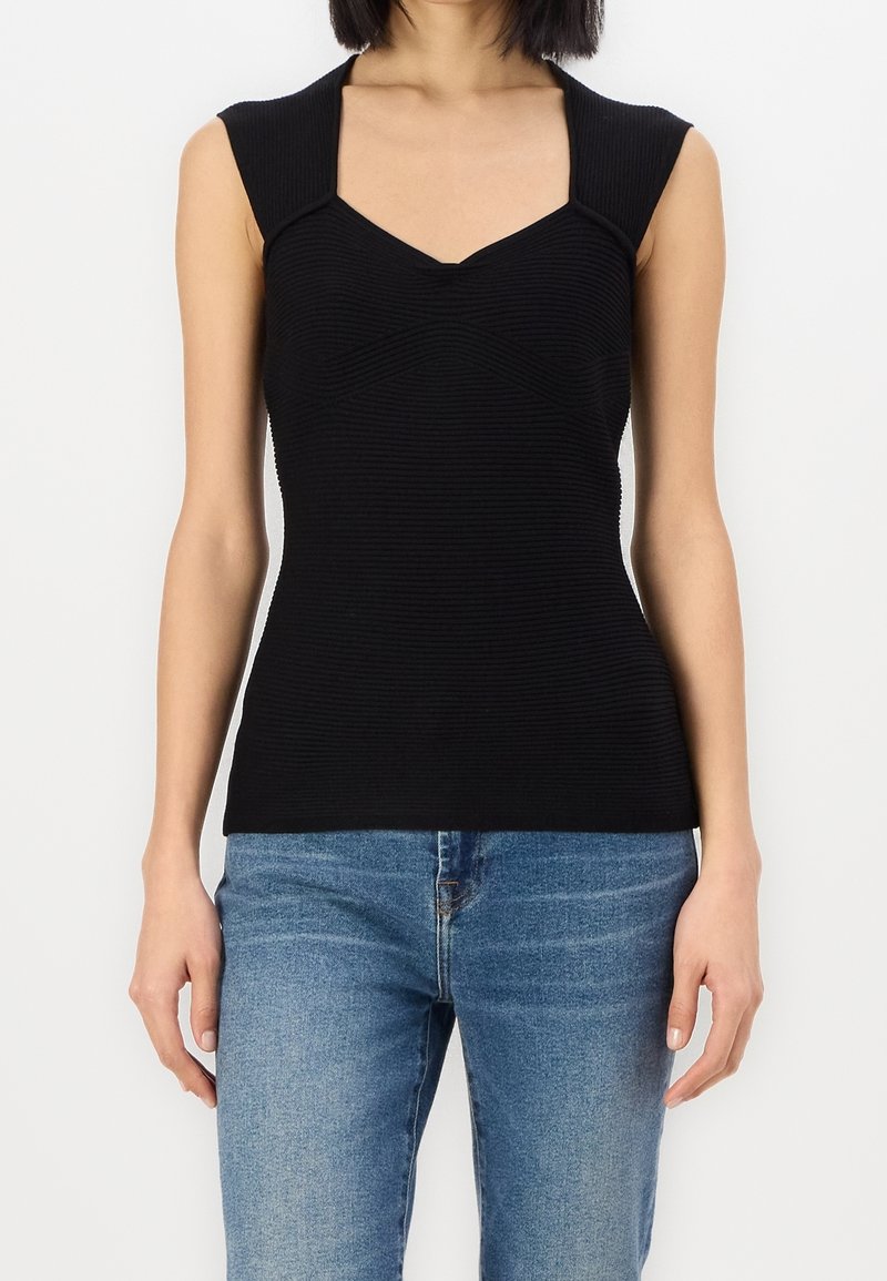 Schwarzes, enganliegendes Oberteil mit gerippter Textur. Verfügt über einen V-Ausschnitt und kurze, strukturierte Ärmel. Kombiniert mit hellblauen Denim-Jeans.
