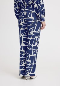 Marineblauwe en crèmekleurige patterned wijde broek met een elastische tailleband, met abstracte vormen en een zachte textuur.