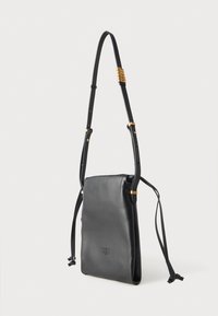 Melnas ādas soma ar šauru taisnstūra formu, regulējamu siksniņu, zelta tonis akcents un vilkšanas slēgšana ar logo iegriezumu detaļām.