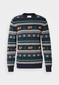 Pull en maille bleu marine avec motif de pins verts, ours bruns portant des écharpes rouges, flocons de neige blancs et dessins géométriques.