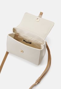 Sac bandoulière de couleur crème avec un extérieur lisse, quincaillerie dorée et une sangle beige réglable. Comprend une poche intérieure.