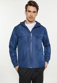 Leichte, blaue Jacke aus glattem Material; verfügt über einen Rei�ßverschluss, zwei Brusttaschen und eine verstellbare Kapuze.