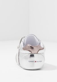 Silberne metallische Sneaker mit rose-goldenen Akzenten an der Ferse. Mit dem Logo "TOMMY HILFIGER" und einer strukturierten Oberfläche. Schnürverschluss-Design.