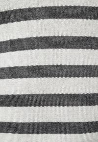 Stickad tröja med växelvis svarta och vita horisontella ränder, med en mjuk struktur och vanlig passform.