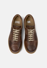Zapatillas de cuero marrón con cordones beige que presentan una punta redondeada y patrones hexagonales en la parte superior. Las etiquetas dicen "Camper" y "Twins."