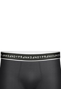 Svarta boxershorts med ett mjukt, elastiskt tyg, med en bred midjeband som är märkt i vitt med "FRANK DANDY"-logotyp mot en svart bakgrund.