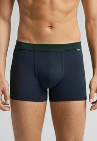 Marina boxershorts med ett grönt elastiskt midjeband, med en mjuk textur och snug passform, designade för komfort och stöd.