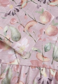 Blommig tyg med en rosa bakgrund som har mönster av persikor, päron och blommor. Texturen verkar mjuk med synliga sömnadsdetaljer.