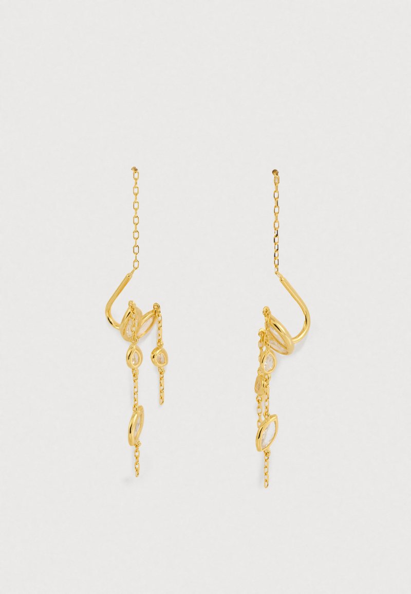 Guldøreringe med aflange abstrakte former, kæder og hængende detaljer; reflekterende overflade med en poleret finish.