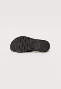 Suola di scarpa in gomma nera con un motivo testurizzato, scanalature per la presa e nome del marchio in rilievo. Design della punta arrotondata per il comfort.