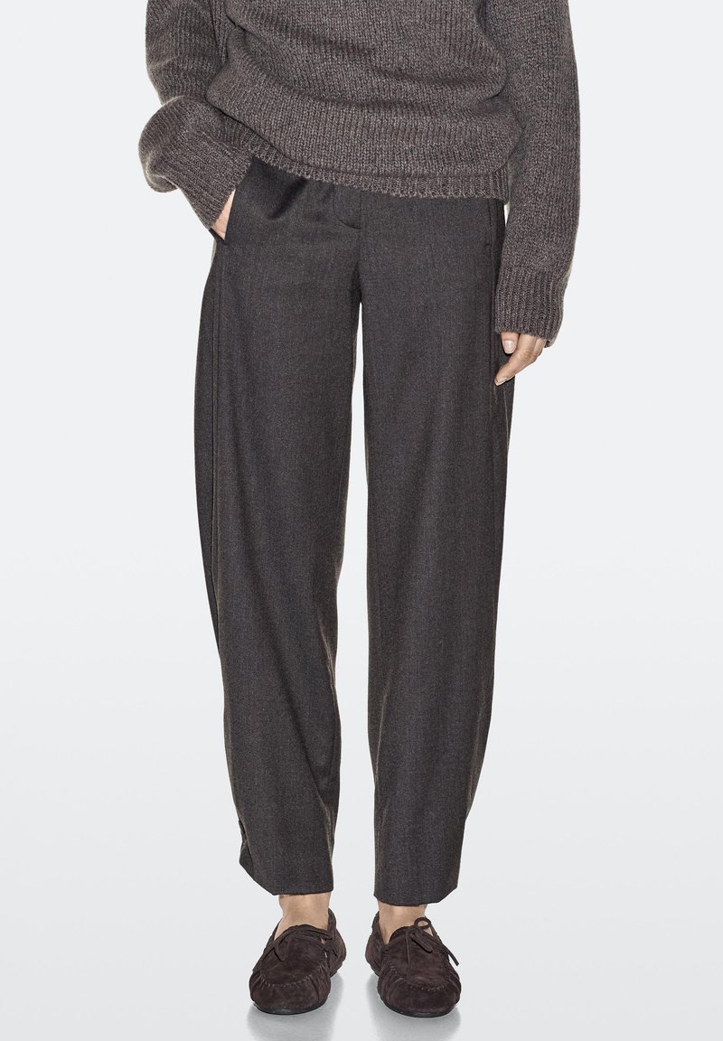 Gray wool trousers with a relaxed fit, featuring side pockets, subtle pleats, and accented by textured brown shoes.