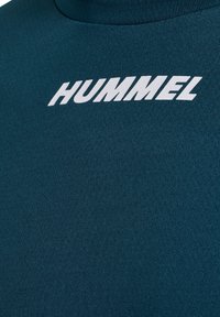 Donker petrolkleurig gestructureerd sportshirt met vet wit HUMMEL-logo gecentreerd op de voorkant.