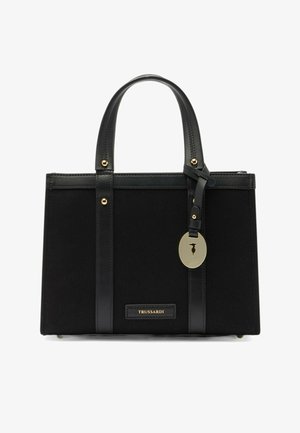 Borsa Trussardi rettangolare nera con doppi manici, fasce verticali in pelle, borchie dorate e un ciondolo ovale dorato appeso a una delle maniglie.