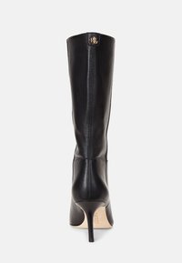 Stivali alti in pelle nera con un design elegante, punta affusolata e tacco a stiletto alto. Presentano un logo dorato nella parte superiore posteriore.