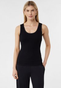 Czarny prążkowany top na ramiączkach z dekoltem typu scoop, wąskimi ramiączkami i miękką fakturą. W komplecie z luźnymi czarnymi spodniami.