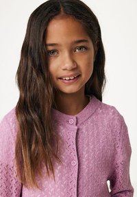 Ljusrosa stickad cardigan med en strukturerad mönster, rund halsringning och två lila knappar. Har långa ärmar och en mjuk finish.