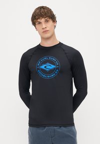 Czarny rash guard z długim rękawem, z niebieskim okrągłym logo z napisem "RIP CURL SURF CO" i "ESTABLISHED 69" na środku.