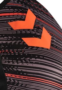 Nærbillede af sort og gråt mønstret stof med horisontale røde linjer og to klare orange geometriske former.