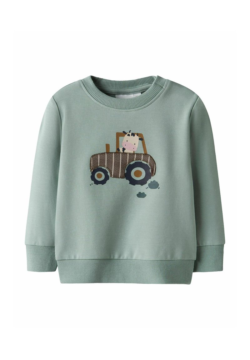 Hellgrüner Sweatshirt mit gerippten Bündchen und Saum. Mit einer Kuh-Illustration in einem braunen Traktor, darunter schwarze Reifenabdrücke.