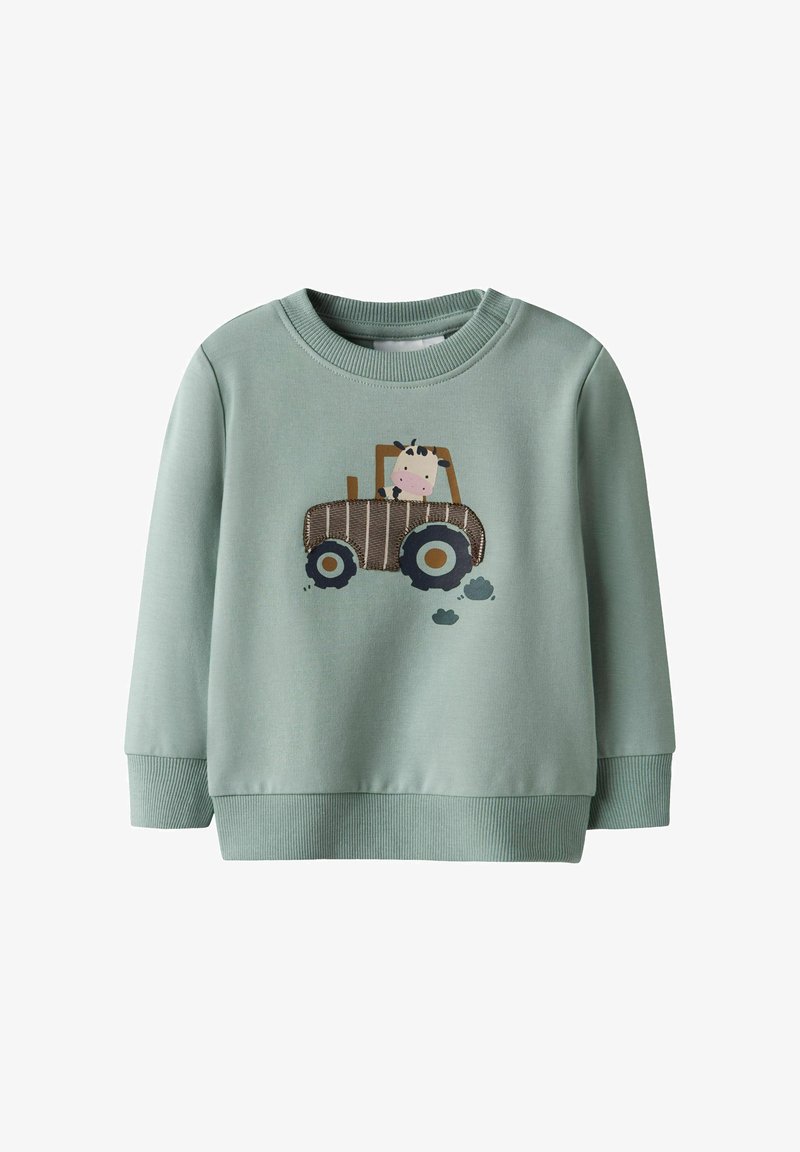 Hellgrüner Sweatshirt mit gerippten Bündchen und Saum. Mit einer Kuh-Illustration in einem braunen Traktor, darunter schwarze Reifenabdrücke.