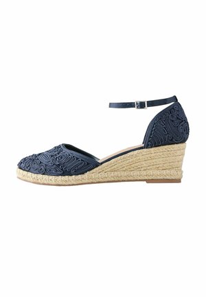 Espadrile plave mornarske boje, klinastog potplata s remenom oko gležnja i složenim vijugavim vezenjem na prstu i peti, klinasti potplat prekriven prirodnim užetom.