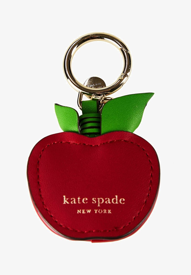 Porte-clés en cuir rouge en forme de pomme avec feuilles vertes et anneau doré, logo « kate spade NEW YORK » imprimé en or sur le devant.