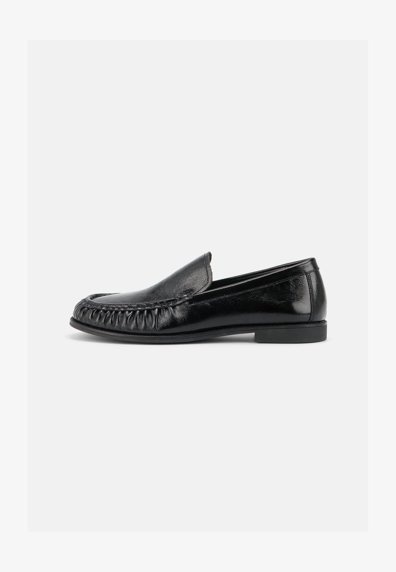Mocassin noir en cuir à enfiler avec bout arrondi, détails cousus à l'avant et petit talon plat, vu de côté.