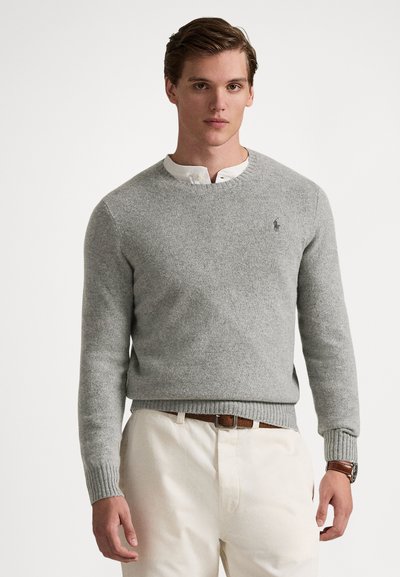 Gray knit sweater with a crew neckline and ribbed hem, paired with a white collared shirt. Features a small logo on the chest.