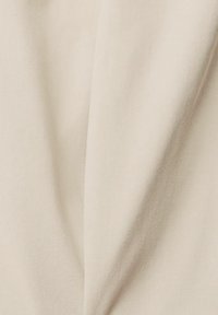 Gros plan sur un tissu beige clair avec une fine texture côtelée diagonale et des plis doux.