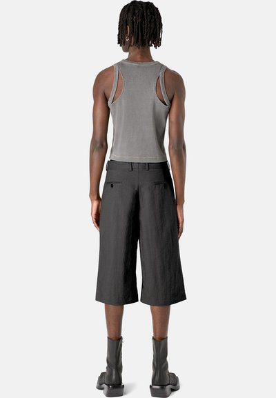 Top de tirantes gris acanalado con detalles recortados, combinado con culottes negros de corte holgado. Botines negros completan el conjunto.