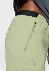 Αθλητικό σορτς ανοιχτό πράσι νο με μαύρη ελαστική μέση, που διαθέτει φερμουάρ και διακριτικό λογότυπο στο ύφασμα. Λεία υφή.