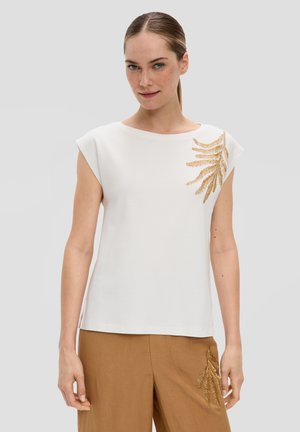 Witte kortemouwen top met een ronde hals en gouden bladborduursel aan de linkerkant. Gladde stof met een relaxte pasvorm.