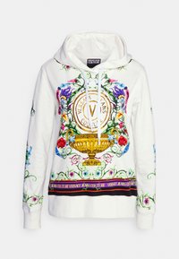 Sudadera blanca con diseño floral y ornamental colorido, gráfico de una urna dorada y texto "Versace Jeans Couture" en el pecho y el dobladillo.