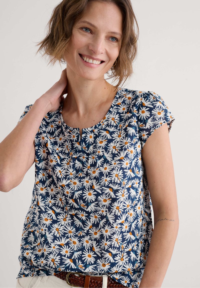 Námořnická blůza s bílým a oranžovým potiskem sedmikrásek, kulatým výstřihem, krátkými nabíranými rukávy, lehkým materiálem a uvolněným střihem.