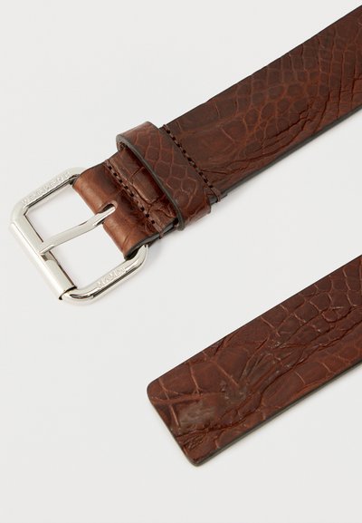 Καστανή δερμάτινη ζωνη με ανάγλυφο σχέδιο, ασημένια ορθογώνια αγκράφα και δερμάτινη θηλιά σε λευκό φόντο.