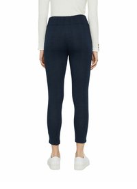 Leggings blu navy con un motivo testurizzato, vita elastica e lunghezza alla caviglia, abbinate a sneakers bianche.