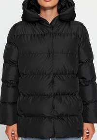 Czarna kurtka puchowa z kapturem, z przeszywanymi sekcjami, z zamkiem błyskawicznym z przodu oraz gładką, elegancką fakturą.
