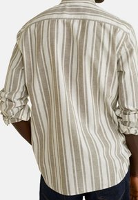Camicia a righe beige e bianca, maniche lunghe, con polsini arrotolati. Realizzata in un tessuto leggero, presenta righe verticali e una vestibilità casual.