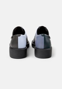 Leder Schuhe mit einem Color-Block-Design in Schwarz, Hellblau, Dunkelblau und Grün, mit einer strukturierten schwarzen Sohle und niedrigem Absatz.