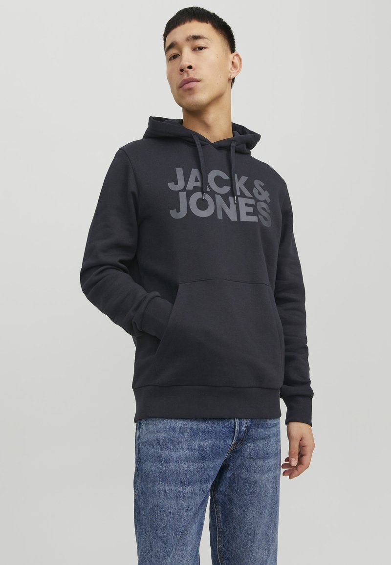Felpa con cappuccio grigio scuro con un grande logo grigio "JACK & JONES", dotata di tasca anteriore e cappuccio regolabile con cordini, abbinata a jeans blu.