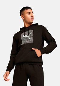 Sudadera negra con bolsillo frontal, un diseño de logo impreso y cordones en la capucha. Fabricada con un tejido suave y un corte relajado.