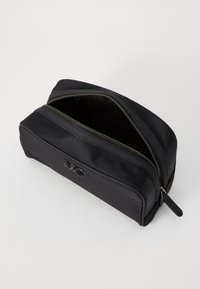 Borsa da toilette in nylon nero con accessori in argento, dotata di doppia cerniera e superficie liscia. Interno foderato e spazioso.