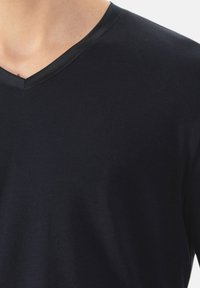 Donkerblauwe V-hals t-shirt van zachte stof, met een gladde, contrasterende zwarte halslijn. Close-up uitzicht op de nek en borstgebied van het shirt.