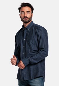 Donkerblauwe button-up shirt van gestructureerde stof, met een borstzak, knoopmanchetten en een casual pasvorm. Gekocht met denim jeans.