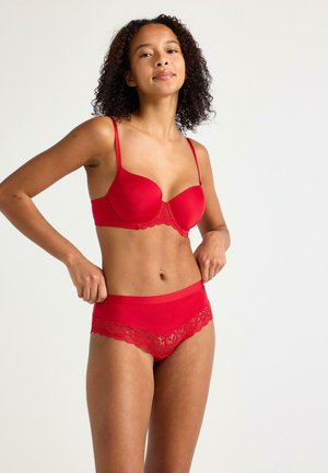 Rode lingerieset met een gepofte bh met kantafwerking en bijpassende slip met kantdetail in de taille en bij de benen. Soepele stofstructuur.