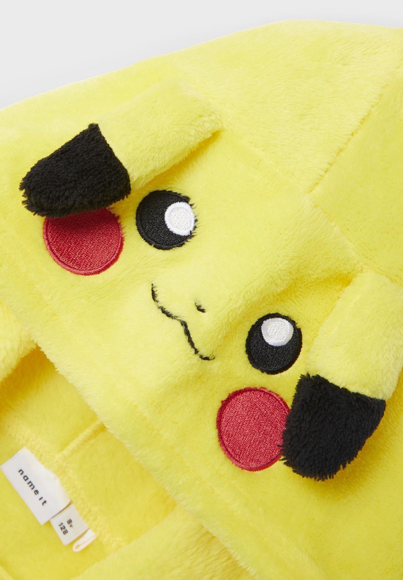 Pikachu-Design Kapuzenpullover, aus gelbem Fleece-Material, mit gesticktem Gesicht, schwarzen Ohren, weißen Augen und roten Wangen. Etikett sichtbar innen.