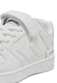 Białe sneakersy z skórzaną cholewką, teksturowanym wzorem, rzepem, okrągłym noskiem oraz wyściełanym kołnierzem z subtelnym logo na pięcie.