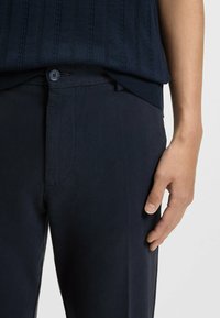 Granatowe, teksturowane spodnie o dopasowanym kroju, z zapięciem na guzik, kieszeniami bocznymi oraz gładkim wykończeniem pasa.