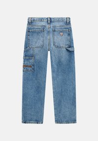 I pantaloni cargo in denim blu presentano un design a gamba dritta, molteplici tasche e un logo ricamato sulla tasca sinistra. Il tessuto ha una texture sbiadita.